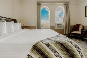 a bedroom with a large white bed with two windows at Hotel St. Michael in Prescott