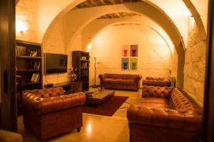 un soggiorno con divani in pelle e TV di Il-Bejta Farmhouse a Għarb