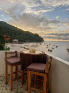 een tafel en stoelen op een balkon met uitzicht op een rivier bij Villa frente al mar en Yelapa para 4 personas in Yelapa