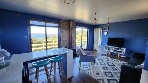 a living room with blue walls and a kitchen with a table at Casa Pascuala in Dalcahue