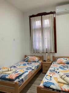 a bedroom with two beds and a window at Aurora Apartment in Kikinda