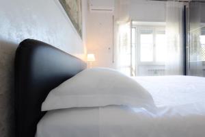 un letto bianco con cuscino in una stanza con finestra di NEW - La Casa di Daniela a Lido di Ostia