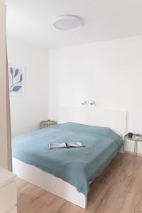 a white bedroom with a bed with a blue blanket at K111 Klapka Apartment in Budapest