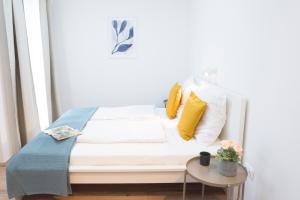 a bed with yellow and white pillows and a table at K111 Klapka Apartment in Budapest