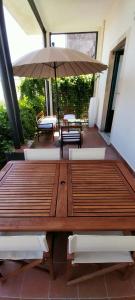 - une table en bois avec un parasol sur la terrasse dans l'établissement BBCasablu, à Acireale