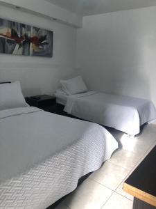 2 camas en una habitación de hotel con 2 colchas en New Memphis Hostal, en Medellín