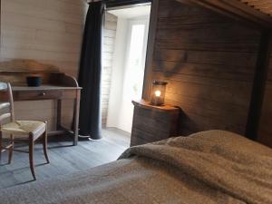 1 dormitorio con cama, escritorio y lámpara en Gîte le lénio en Langogne