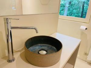 La salle de bains est pourvue d'un évier à seau sur un comptoir. dans l'établissement Prachtige chalet in het bos met sauna!, à Lanaken