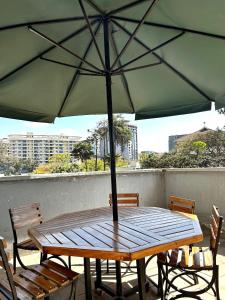 a wooden table with an umbrella on a balcony at Lovely 2bedroom Apartment overlooking Nairobi City in Nairobi
