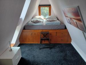 1 dormitorio con 1 cama en una cómoda de madera y una ventana en Ferienhaus Elbliebe - kleine Hunde bis 25 cm willkommen en Dannenberg