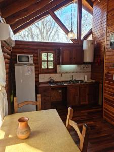 a kitchen with a table and a refrigerator at Cabañas La Ponderosa in Villa Ventana