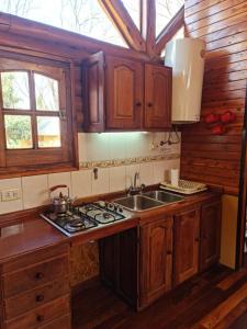 a kitchen with wooden cabinets and a sink and a stove at Cabañas La Ponderosa in Villa Ventana