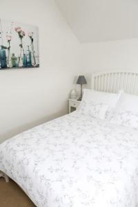 a bedroom with a white bed with flowers on it at Detached Cotswold Stone Coach House in Cheltenham