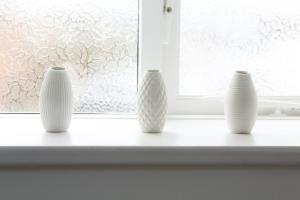 three white vases sitting on a window sill at Detached Cotswold Stone Coach House in Cheltenham