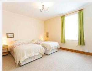 two beds in a bedroom with green curtains at Fishermen Cottage - 5 star location- 90sq garden -2 living room- 2 bath room -pets friendly -comfortably sleep 5-6 people -50 percent off monthly -self check in in Deal
