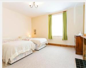 two beds in a bedroom with green curtains at Fishermen Cottage - 5 star location- 90sq garden -2 living room- 2 bath room -pets friendly -comfortably sleep 5-6 people -50 percent off monthly -self check in in Deal