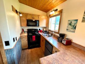 a kitchen with a black stove and a sink at Glacier's Edge Cabins in Columbia Falls