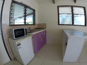una pequeña cocina con armarios morados y microondas en Ranginui Sunset, en Arutanga