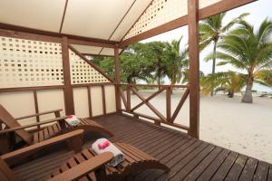 eine Veranda mit 2 Stühlen und Strandblick in der Unterkunft Ranginui Sunset in Arutanga