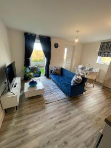 Una sala de estar con un sofá azul y una mesa. en Luxurious Apartment in Brooklands, en Milton Keynes