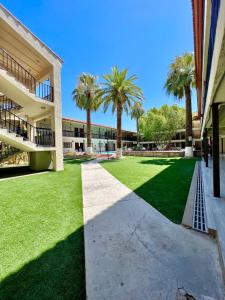 a walkway in front of a building with palm trees at Hotel Bugambilia in Hermosillo