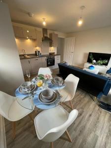 uma mesa de jantar com cadeiras brancas numa cozinha em Luxurious Apartment in Brooklands em Milton Keynes