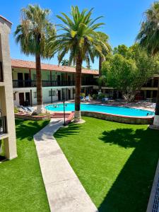 a courtyard with palm trees and a swimming pool at Hotel Bugambilia in Hermosillo