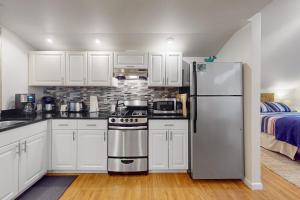 a kitchen with white cabinets and a stainless steel refrigerator at St. Moritz- Apartment in Girdwood