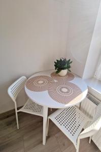 Apartments in Lazdijai في لازديجاي: طاولة بيضاء عليها كرسيين وزرع