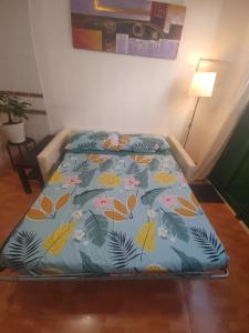 ein Bett mit einer blauen Bettdecke mit Blumen und Blättern in der Unterkunft Playa Celeste Tajao in La Mareta