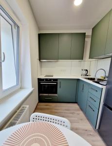 Apartments in Lazdijai في لازديجاي: مطبخ صغير مع دواليب خضراء وطاولة