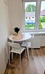 Apartments in Lazdijai في لازديجاي: طاولة بيضاء وكراسي في غرفة مع نافذة