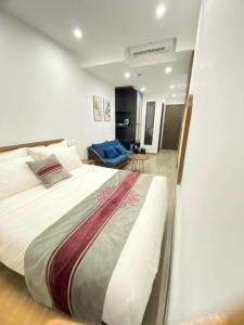 a bedroom with a large bed and a blue couch at GOODTECH LUXURY Hotel & Apartment in Danang