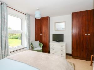 a bedroom with a bed and a tv and a window at Kathy's Cottage in Kings Lynn
