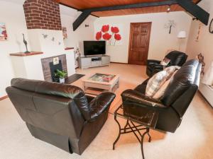 a living room with two leather chairs and a tv at The Stables in Flemingston