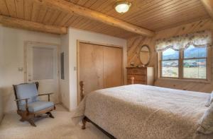 1 dormitorio con 1 cama, 1 silla y 1 ventana en Moonlight Cabin, en Creede