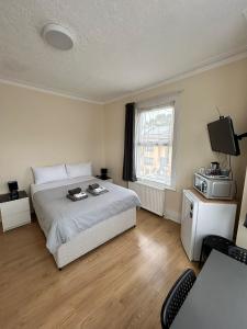 a bedroom with a bed and a television and a desk at WIllesden Lodge Guest House in London