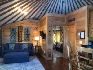 ein Wohnzimmer mit einem blauen Sofa und ein Schlafzimmer in der Unterkunft Fontana @ Sky Ridge Yurts in Bryson City