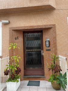 a brown door on a brick building with two potted plants at Rio de Janeiro Botafogo Zona Sul in Rio de Janeiro