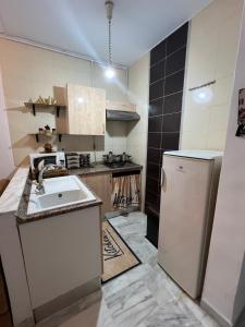 a small kitchen with a sink and a refrigerator at Appartement L'aouina cité wahat in Tunis