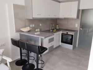 a kitchen with white cabinets and black bar stools at AFRODITE in Diakopto