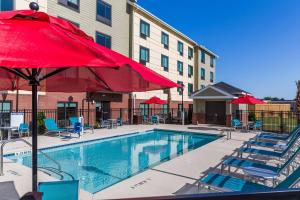 a pool with a red umbrella and chairs and a building at TownePlace Suites by Marriott Florence in Florence