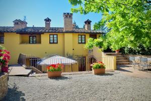 a yellow house with two potted plants in front of it at Relax in Chianti IL BORGO 8 in Montespertoli