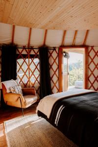 a bedroom with a bed and a chair and a window at Junaluska @ Sky Ridge Yurts in Bryson City