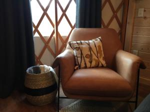 a brown chair with a pillow in front of a window at Junaluska @ Sky Ridge Yurts in Bryson City