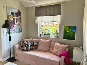 a pink couch in a living room with a window at Apartament Różany in Kopalino