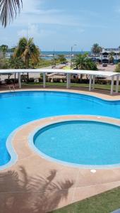 una gran piscina con el océano en el fondo en Nautica Beach - Moderno Apartmento Margarita, en Porlamar