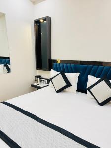 HOTEL Red Rosse في نيودلهي: غرفة نوم مع سرير أبيض مع اللوح الأمامي الأزرق