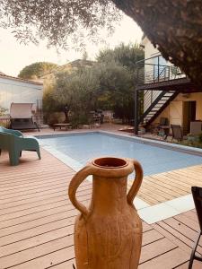 un jarrón sentado en una terraza junto a una piscina en Appartement indépendant avec jardin et accès piscine, en Nimes