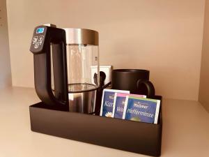 a coffee maker and books on a black shelf at MEA HOTEL TRIER in Trier